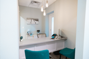 BZ Orthodontics office interior featuring a reception area with a desk, teal chairs, and modern decor, representing orthodontic services like Invisalign in Lansdale, PA.