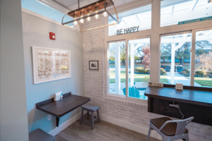 Bright and inviting waiting area at BZ Orthodontics featuring a wooden table, contemporary lighting, and large windows with outdoor views, promoting a welcoming atmosphere for patients in Lansdale, PA.
