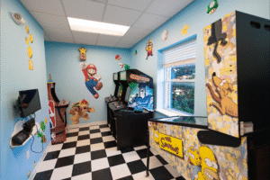 Game room at BZ Orthodontics featuring arcade machines and colorful wall decorations, designed for a fun atmosphere for patients, including characters from popular video games and cartoons, enhancing the experience for families in Lansdale, PA.