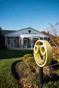 BZ Orthodontics office exterior in Lansdale, featuring a prominent yellow logo, inviting atmosphere, and landscaped surroundings, highlighting services like Invisalign and braces.
