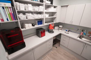 Orthodontic office workspace at BZ Orthodontics, featuring organized shelves with dental supplies, a red dental device, and a sink, illustrating a professional environment for orthodontic services in Lansdale, PA.