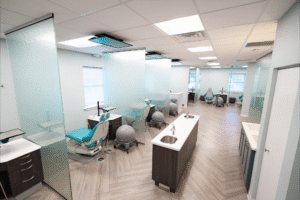 Modern orthodontic office interior at BZ Orthodontics in Lansdale, featuring treatment areas with turquoise dental chairs and glass partitions, emphasizing a welcoming environment for Invisalign and braces consultations.