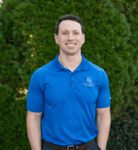 Dr. Brian Zebrick, orthodontist at BZ Orthodontics, smiling in a blue polo shirt against a green backdrop, promoting orthodontic services including Invisalign and braces in Lansdale, PA.