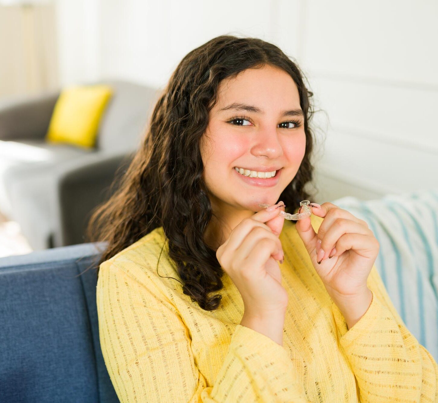 Smiling teen girl holding a clear aligner