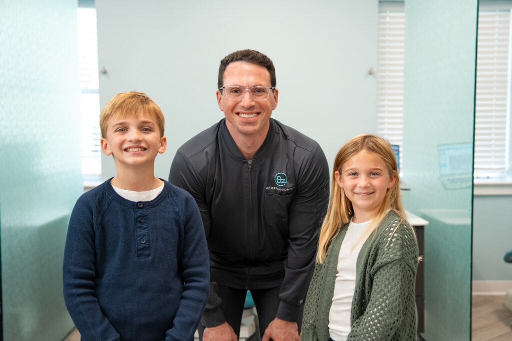 Dr. Zebriek with two young patients smiling in Lansdale orthodontics office, promoting BZ Orthodontics and services like Invisalign and braces.