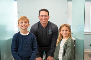 Dr. Zebriek with two young patients smiling in Lansdale orthodontics office, promoting BZ Orthodontics and services like Invisalign and braces.