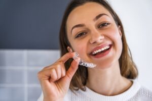 Adult patient holding clear aligners.