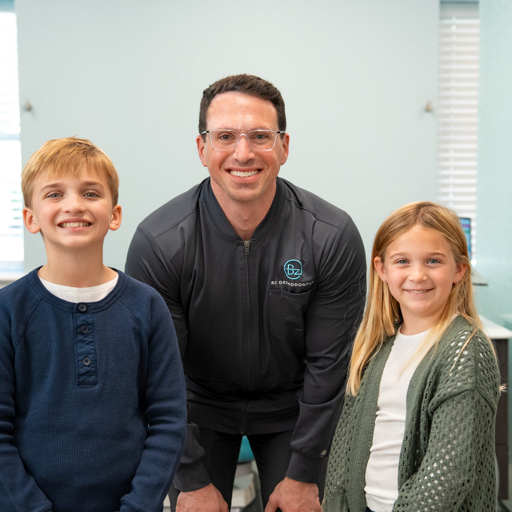 Dr. Zebrick smiling with two young patients in the BZ Orthodontics office