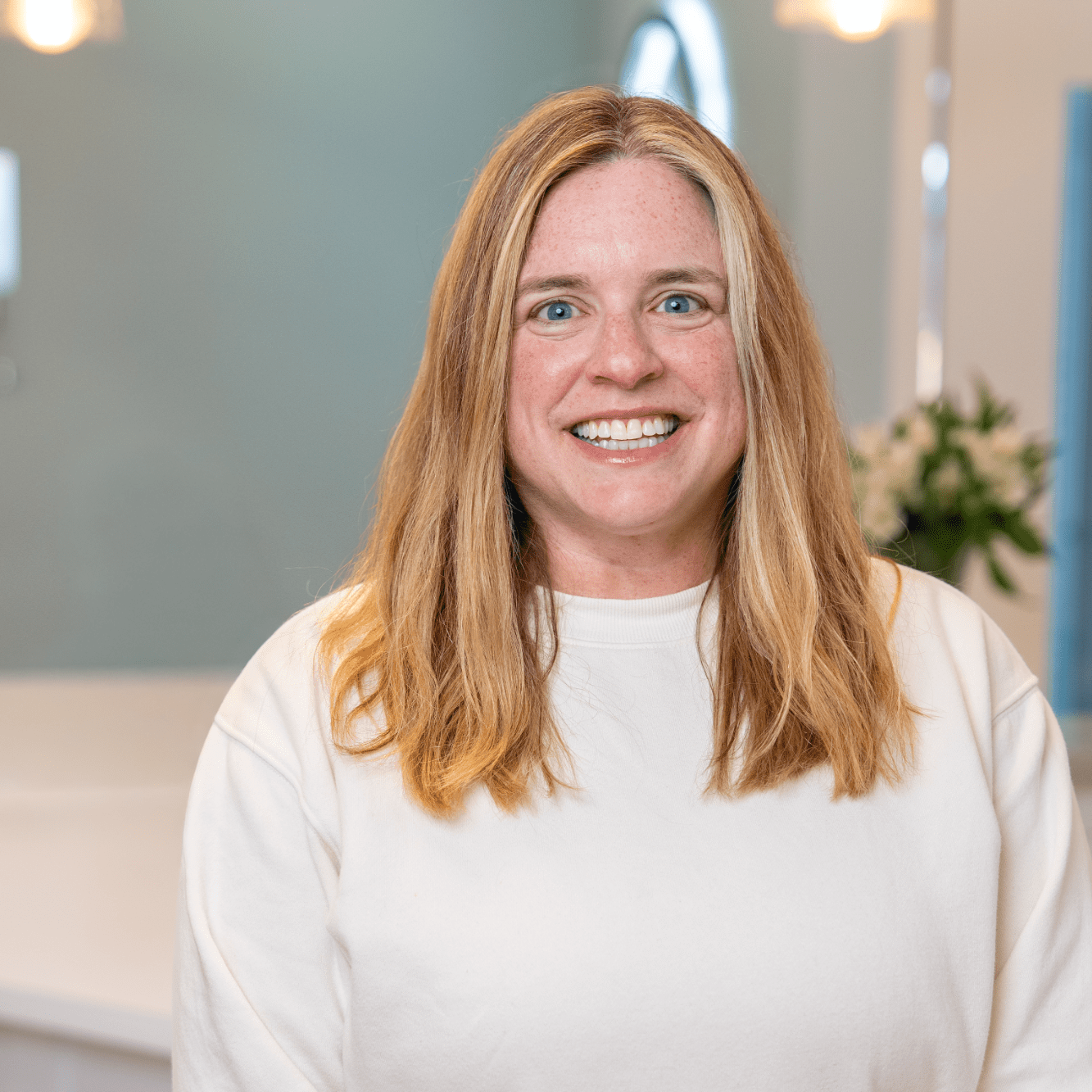 Smiling woman with long hair in a dental office, showcasing a straight smile, representing BZ Orthodontics and Dr. Zebrick's clear braces treatment in Lansdale.