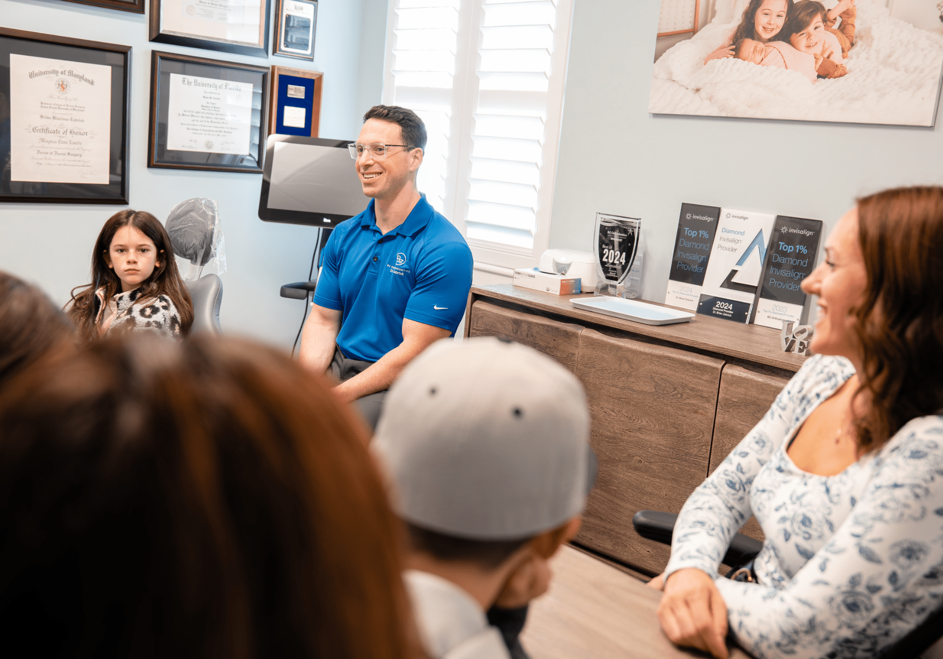 Dr. Zebrick engaging with patients in a consultation room at BZ Orthodontics, featuring awards for Invisalign and a welcoming atmosphere for families in Lansdale, PA.