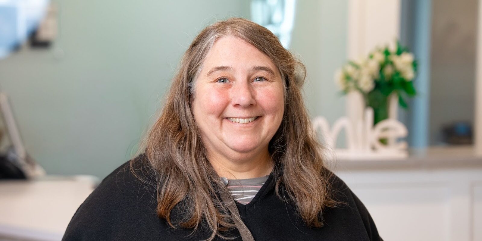 Smiling woman in BZ Orthodontics office, showcasing positive patient experience with Dr. Zebrick, highlighting friendly atmosphere and orthodontic care in Lansdale, PA.