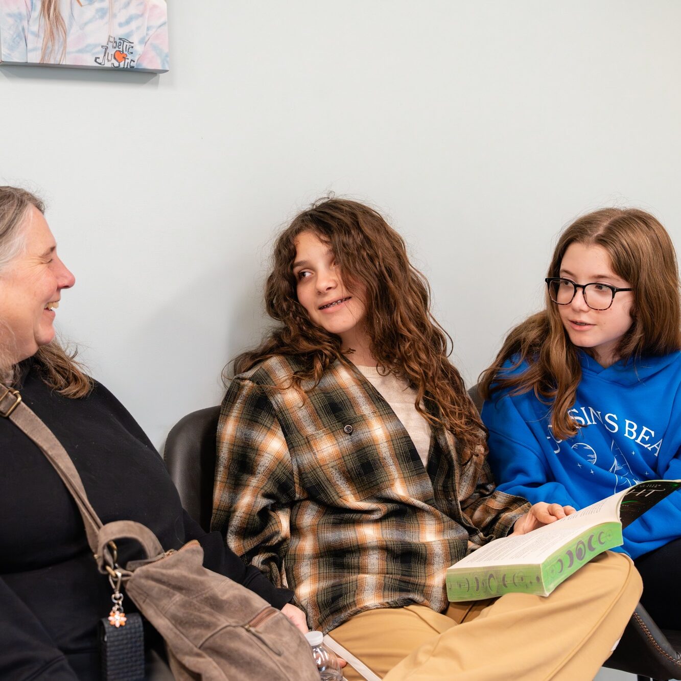 Two young girls and an adult woman chatting in a waiting area at BZ Orthodontics, showcasing a friendly atmosphere for patients seeking orthodontic care in Lansdale, PA.